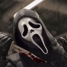 a man in a hooded jacket holding a knife and wearing a scream mask with his mouth open