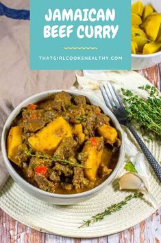 jamaican beef curry in a white bowl on a wooden table with a fork and spoon next to it