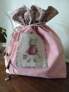 a pink bag with a cross stitch design on it