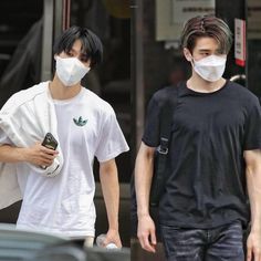 two young men wearing face masks walking down the street