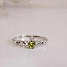 What Is The Claddagh? The Claddagh Ring Is A Traditional Irish Ring Which Represents Love, Loyalty, And Friendship (The Hands Represent Friendship, The Heart Represents Love, And The Crown Represents Loyalty). Top Of Ring Width: 16.6mm Band Width: 1.4 Mm Stone Material: Simulated Peridot And Clear Cz Center Stone Size: 4.1mm Stone Shape: Heart Shape (Center) & Round Total Number Of Stones: 2 Stone Setting: Prong Setting Metal: 925 Sterling Silver Finish: High Polish K E E P I N T O U Ch Https:// Sterling Silver Diamond Ring With May Birthstone, Sterling Silver Diamond Ring For May Birthstone, Sterling Silver Diamond Birthstone Ring For May, Sterling Silver Diamond Promise Ring For May, White Promise Ring For May Birthstone, Sterling Silver Heart Rings For May Birthstone, White Gold Birthstone Ring Stamped 925 For Promise, Silver Diamond Promise Ring For May Birthstone, Sterling Silver White Gold Ring For May Birthstone