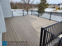 a deck with black iron railings next to a house