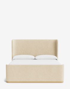 an upholstered bed with two pillows on it