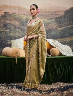 This chic tissue sari is an exquisite embodiment of timeless elegance, featuring delicate dabka work and a gotta patti border adorned with ghumroos. Paired with a chanderi silk blouse embellished with intricate mirror work, this ensemble blends traditional craftsmanship with a modern flair, perfect for elevating your festive look. Eid Silk Pre-draped Saree With Gota Work, Festive Gold Pre-draped Saree With Mirror Work, Dola Silk Chandbali Pre-draped Saree For Diwali, Gold Chanderi Pre-draped Saree With Gota Work, Gold Pre-draped Saree With Sheer Dupatta For Navratri, Bollywood Style Tissue Silk Pre-draped Saree For Designer Wear, Party Pre-draped Saree With Gota Work, Designer Chinon Pre-draped Saree For Diwali, Designer Pre-draped Dola Silk Saree With Dupatta