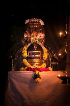 the statue is decorated with flowers and garlands on it's head, surrounded by candles