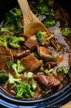 beef and broccoli are being cooked in the crock pot with a wooden spoon