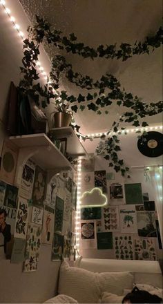 a living room filled with lots of plants and lights hanging from the ceiling above it