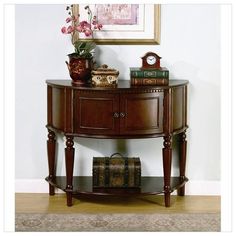 a wooden console table with books on it and a clock sitting on top of it