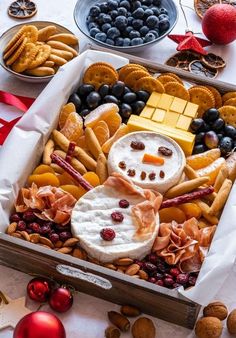 an assortment of cheeses, crackers and fruit arranged in a snowman box