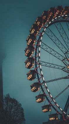 the ferris wheel is lit up in the dark blue sky with lights on it's sides