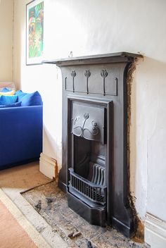 a fireplace in a living room next to a blue couch and painting on the wall