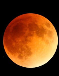 an orange moon is seen in the dark sky