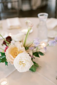 a white table with flowers and candles on it