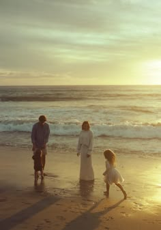 a family standing on the beach at sunset