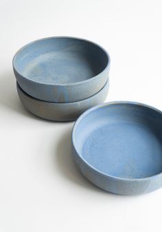 two blue bowls sitting next to each other on a white surface