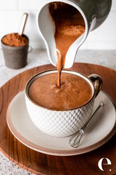 chocolate being poured into a white bowl on top of a wooden plate with spoons