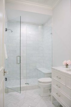 a white bathroom with a glass shower door