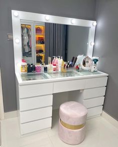 a white vanity with lights on it and a stool