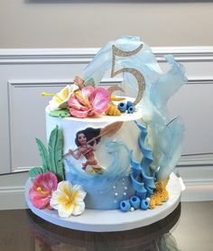 a cake decorated with flowers and the number five on it's top is sitting on a table