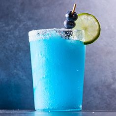 a blue drink with a lime slice on the rim