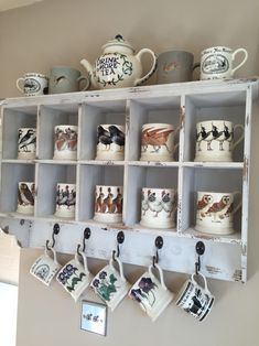 mugs and cups are hanging on a shelf