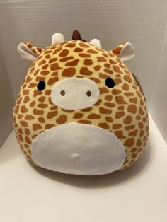 a giraffe stuffed animal sitting on top of a white counter next to a wall