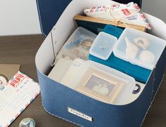 an open suitcase filled with various items on top of a wooden table next to a postcard