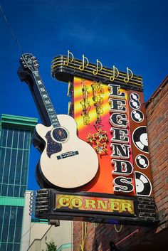 a sign for a music venue with a guitar hanging off the side of it's building