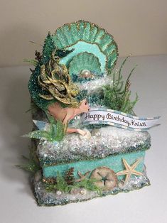 a figurine is sitting on top of an ocean themed box with a happy birthday message