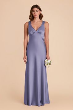 a bridesmaid in a blue dress holding a bouquet and posing for the camera