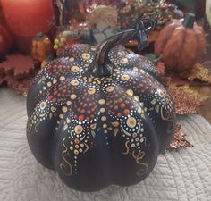 a painted pumpkin sitting on top of a white cloth covered table next to candles and other decorations