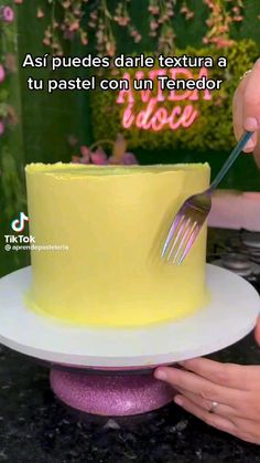 a person cutting into a yellow cake with a fork