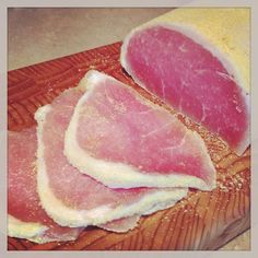 two pieces of meat sitting on top of a cutting board next to another piece of meat