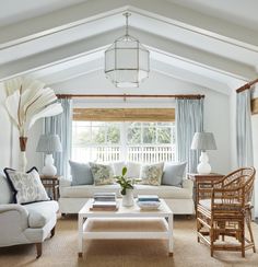 a living room with white furniture and blue curtains