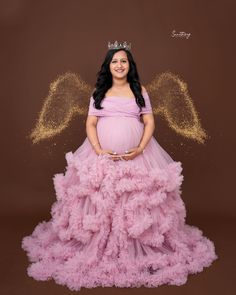 a pregnant woman in a pink gown with angel wings