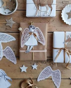 christmas wrapping with angel cutouts and star decorations on wooden table next to wrapped gifts