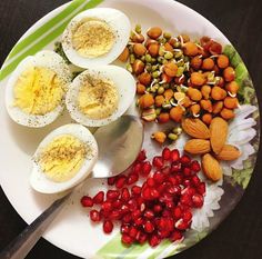 an assortment of food on a plate including hard boiled eggs, nuts and pomegranates