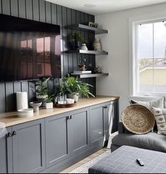 a living room filled with furniture next to a window and a flat screen tv mounted on the wall