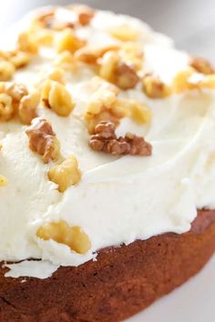 a cake with white frosting and walnuts on top is sitting on a plate