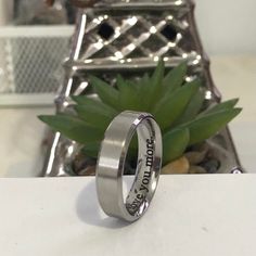 a silver ring sitting on top of a table next to a plant