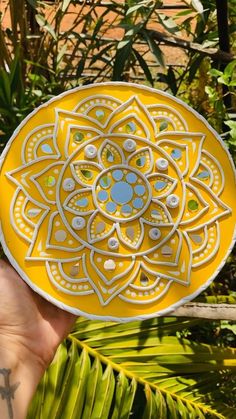 a person holding up a yellow plate with designs on it