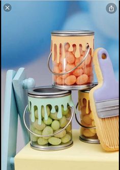 three tins filled with candy sitting on top of a table next to a brush