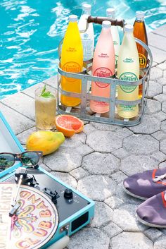 an assortment of drinks sitting next to a swimming pool