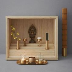 a wooden box with candles and a buddha statue in the middle on a grey surface