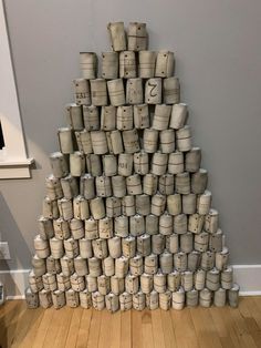 a large stack of cups sitting on top of a wooden floor next to a wall