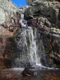 there is a waterfall in the middle of some rocks