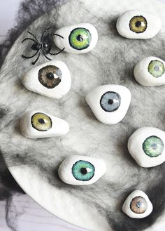 some fake rocks with eyes painted on them sitting on a white plate next to a spider