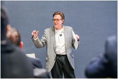 a man standing in front of a crowd holding his hands out to the side while talking