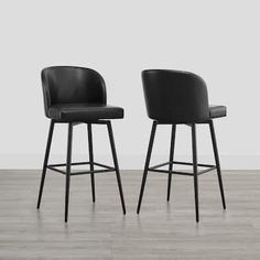 two black leather bar stools in front of a white wall