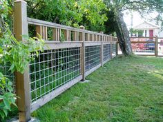 the fence is made from wood and metal wire, with green grass in front of it